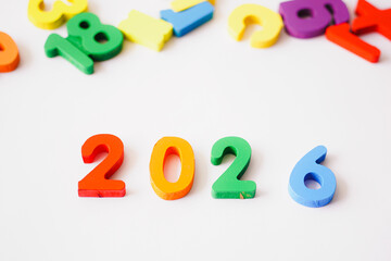Naklejka premium Cheerful colorful wooden blocks forming 2026 on white background, New Year celebration concept
