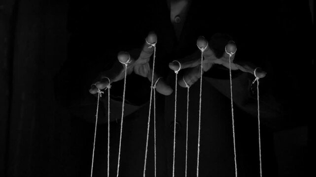 The puppeteer controls the puppets in the theater. Managing people at work, in politics and government. Action control. Black and white image.