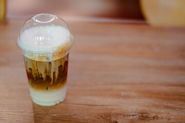 Glass of iced coffee on wooden table in coffee shop.