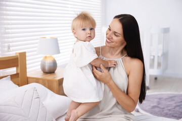 Mother and her cute little baby on bed in room