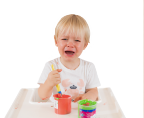 Little blond boy crying sitting on a baby chair playing with painting over transparent background. PNG transparent