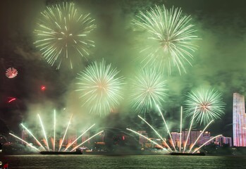 Vibrant green fireworks over city skyline.
