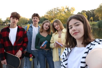 Group of teenagers taking selfie near lake outdoors