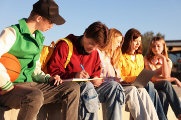 Obraz premium Group of teenagers doing homework together outdoors
