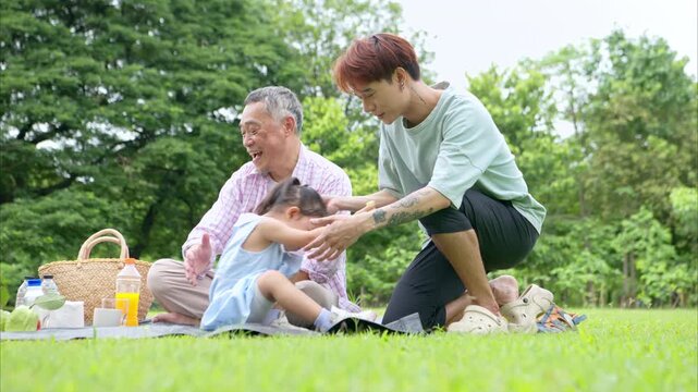 Happy multi generational Asian family enjoying picnic in the park,  Creating joyful outdoor lifestyle moment