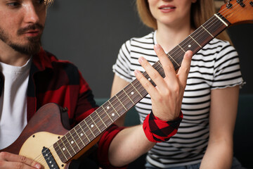 Obraz premium Tutor teaching woman to play guitar at home, closeup