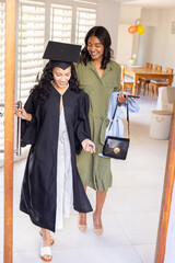 Diverse mom and teenage daughter stepping through wooden doorway at home entryway holding keys
