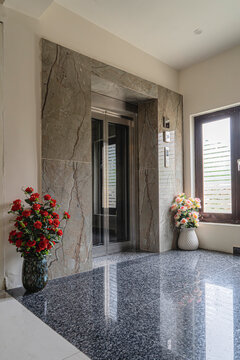 The elevator door is in a spacious hall with a window. Faye in hotels, entrance decorated with flowers