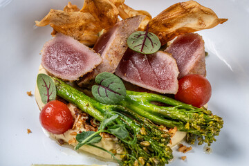 Seared tuna steak with vegetables and garnish.