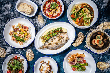 Assorted gourmet seafood and vegetable dishes on table.
