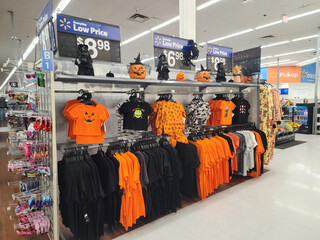 Editorial stock photo of a Walmart store interior in Cary, North Carolina, USA, with Halloween decorations, seasonal costumes, pumpkin designs, themed T-shirts and clothing on display for sale.