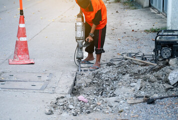 Worker demolish existing concrete road by jack hammer for repair concrete floor. Surface road construction by drilling cement ground.