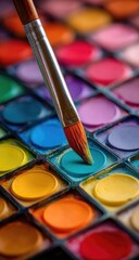 Close-up of artist's paintbrush dipping into a vibrant palette of color