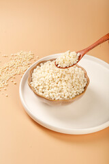 White sorghum grains in wooden bowl with wooden spoon - healthy gluten-free cereal grain