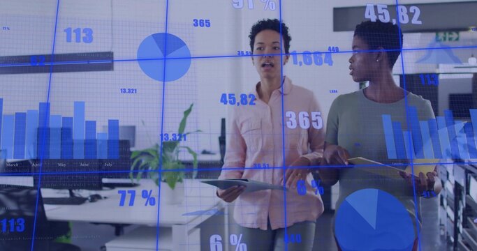 Walking business casual women discussing live data in office, with tablets and holographic charts