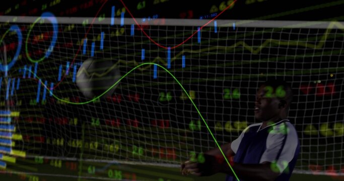 Standing male athlete tracking incoming ball in goal at night, with financial charts, copy space - Powered by Adobe