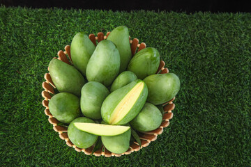 Fresh Green Mangoes in Woven Basket on Grass - Tropical Fruit Display