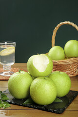 Fresh Green Apples on Slate Board with Wicker Basket and Water Glass