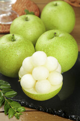 Fresh Green Pears Display with Cut Pear Showing White Flesh on Dark Slate Board