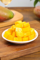 Fresh Ripe Mango Cubes in Bowl on Wooden Board with Whole Mangoes