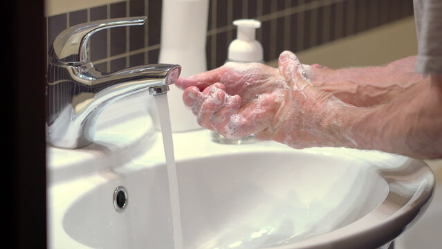 The concept of protecting the body from germs and viruses. Close up hands of senior man that applying lather and soap to make cleaning from germ, bacteria. Protect youself from infection