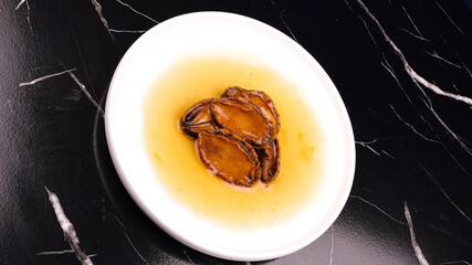 Fresh Abalone Shellfish in White Dish on Dark Marble - Premium Seafood Delicacy for Fine Dining