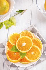 Fresh Juicy Orange Slices from Guangxi China on White Plate with Green Leaves Rustic Wood Background