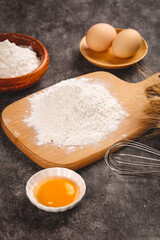 Fresh baking ingredients with flour, eggs and wheat for homemade bread making on rustic kitchen surface
