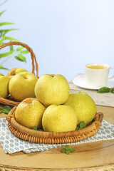 Fresh Asian Pears in Wicker Basket with Tea Cup Still Life on White Wood Table