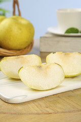 Fresh pear slices on white cutting board with shallow depth of field kitchen scene
