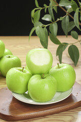 Fresh Green Apples Display on Wooden Table with Natural Plant Background