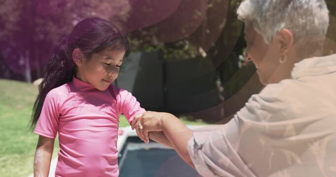 Woman unscrewing sunscreen and rubbing lotion across child's forearm for pool skincare, flares