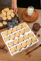 Traditional Asian golden egg pastries in organized array with milk and spices on wooden table
