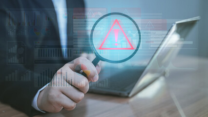 Businessman using tablet with warning alert icon, cyber security, risk management, and data protection in digital business.