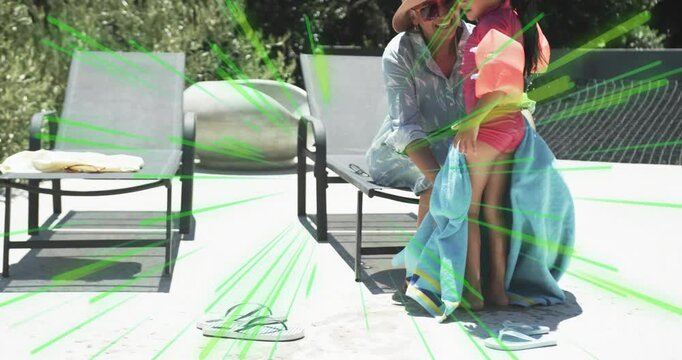Mother grabbing towel after swim and wrapping floaties-clad daughter for sun safety on pool deck