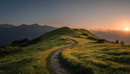 Winding path ascends a grassy hillside at sunrise.  Mountain backdrop