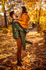 Romantic couple bonding in a sunny autumn park surrounded by colorful foliage and enjoying the seasonal beauty together