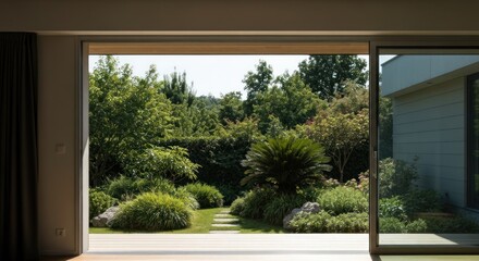 Wide view of a modern home's patio, through glass sliding doors, showcasing a lush garden beyond