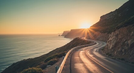 Winding road hugs coastal cliffs at sunset.  Golden sun rays illuminate the ocean horizon