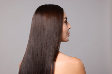 Woman with beautiful smooth hair after lamination procedure on light grey background