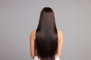 Woman with beautiful smooth hair after lamination procedure on light grey background, back view