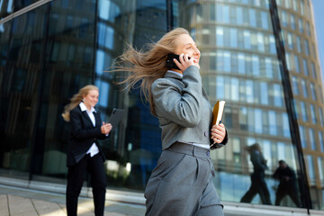 Woman in suit talking on phone near modern building