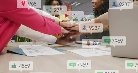 Colleagues placing hands initiating collaboration, social media icons floating driving engagement - Powered by Adobe