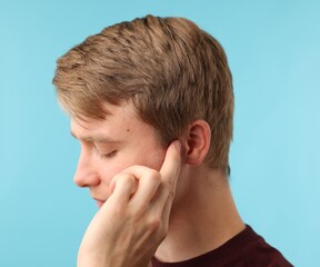 Sound. Man with hearing problem on light blue background