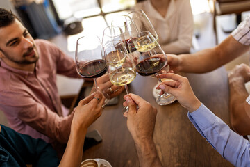 Group of young friends in modern cafe raising glasses in toast