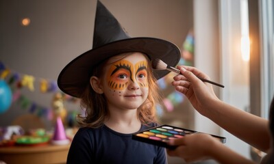 A young girl, likely for Halloween, has face paint being applied.  A witch hat and colorful face paint are prominent.  The image shows a moment of preparation for a costume party