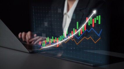 A business professional focuses on analyzing a digital stock market graph on a laptop, showcasing financial data and an upward growth trend in a modern office environment. Copula