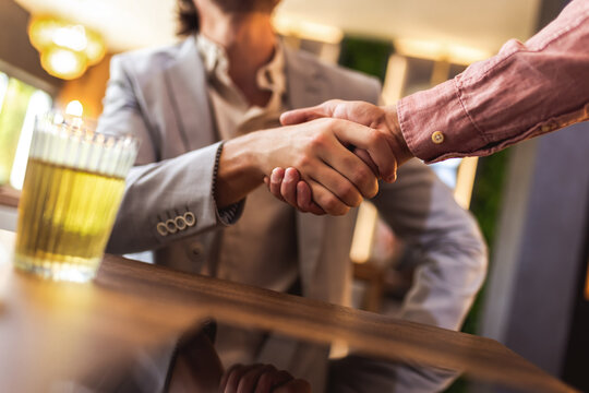 Close up of handshake between two people in modern cafe, symbol of agreement, partnership and connection.