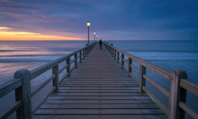 Obraz premium Tranquil sunrise over a wooden pier. A solitary figure walks towards the horizon