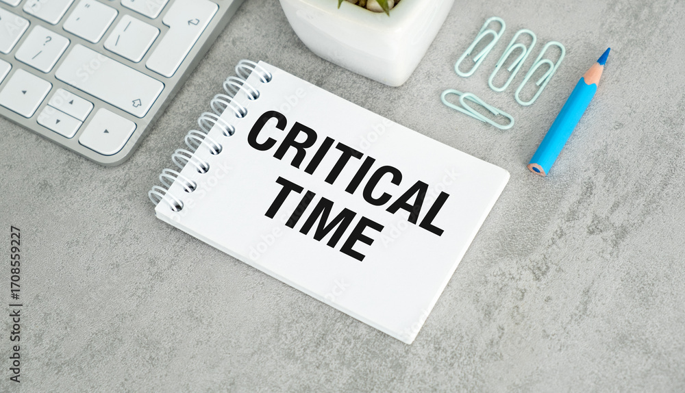 Aufkleber critical time text on open notebook with keyboard buttons and office supplies on grey table